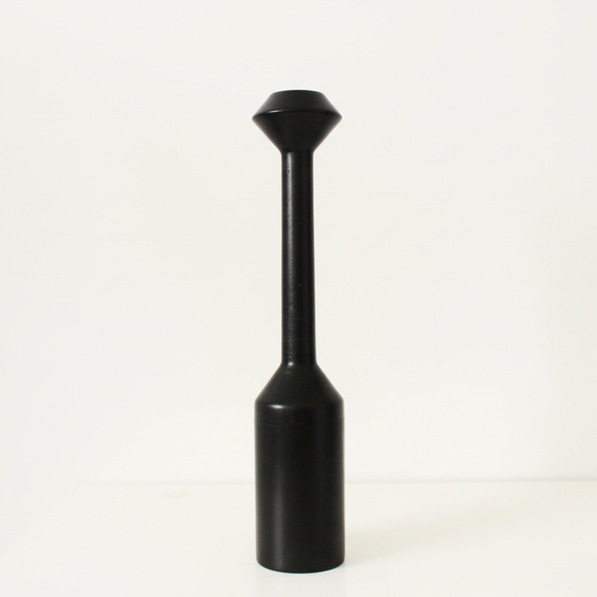 Black cylindrical large wooden candle holder with a conical top on a white background. Earthy and natural home decor. 