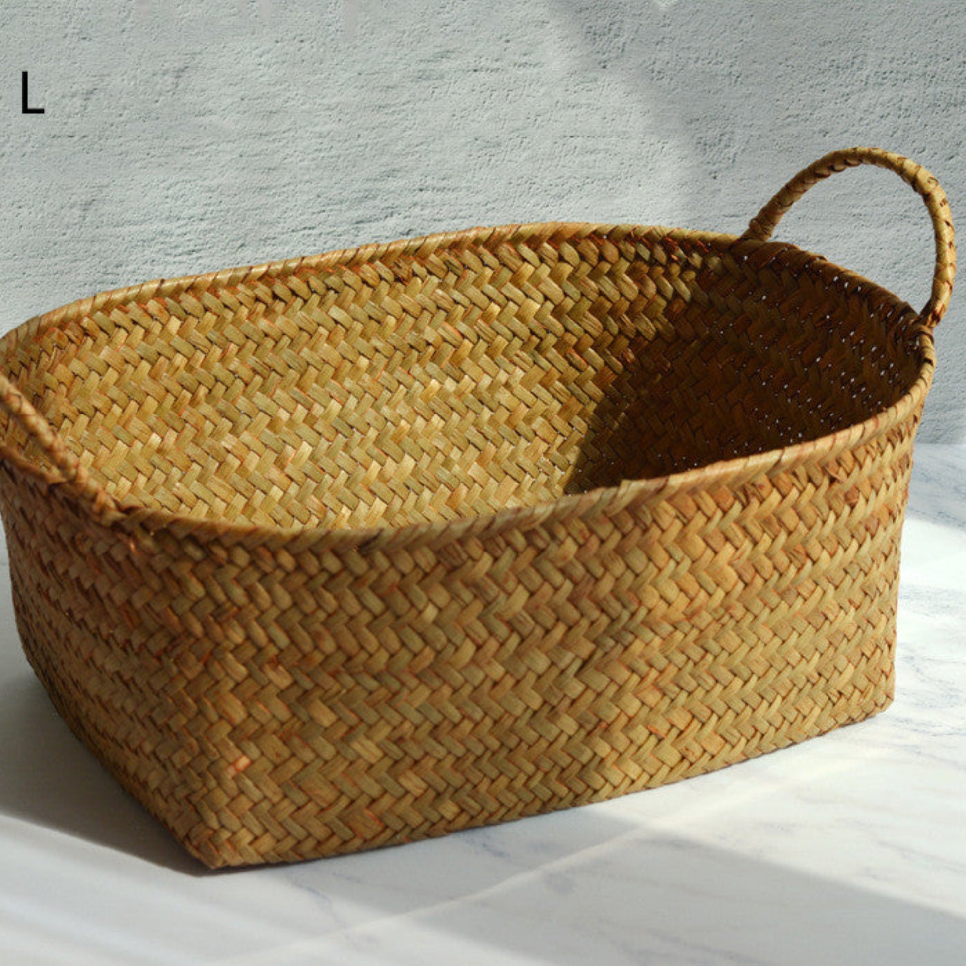 Woven basket with handles on a light background. Scandinavian decor inspired by simplicity and warm tones. Earthy tones for storage. 
