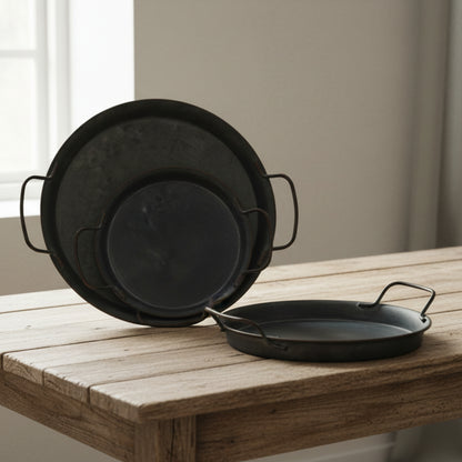 Three wrought iron trays with handles on a wooden table and a blurred white-beige background. Minimalist black decor centerpiece. 